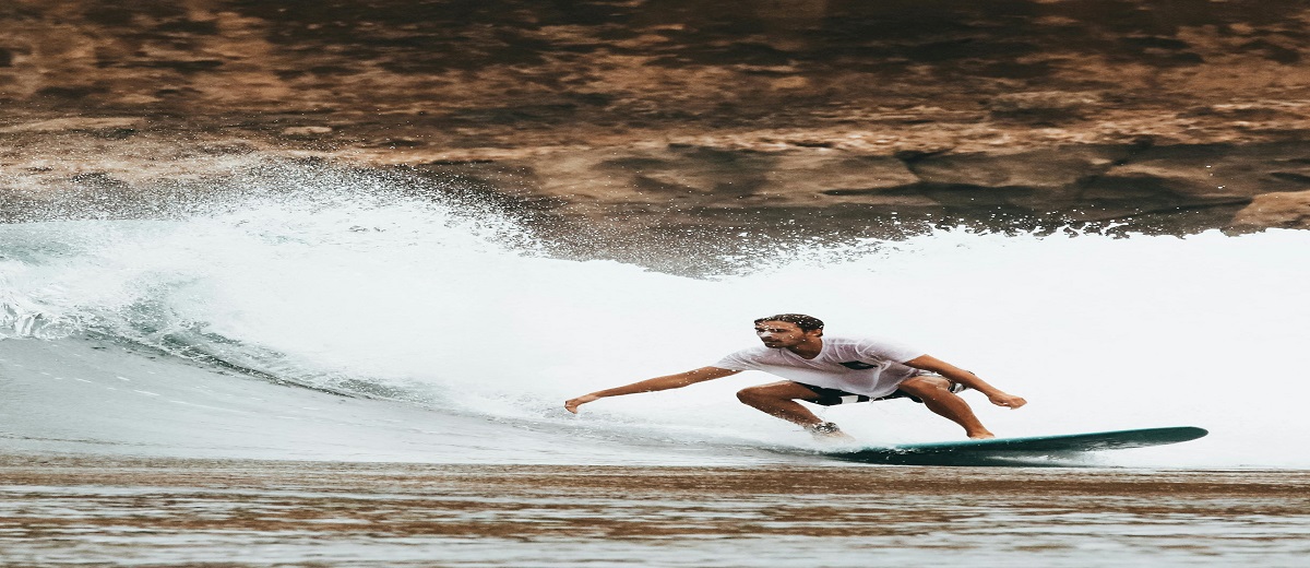 Surfista usando wetsuit de neoprene saindo do mar após sessão de surf em água fria